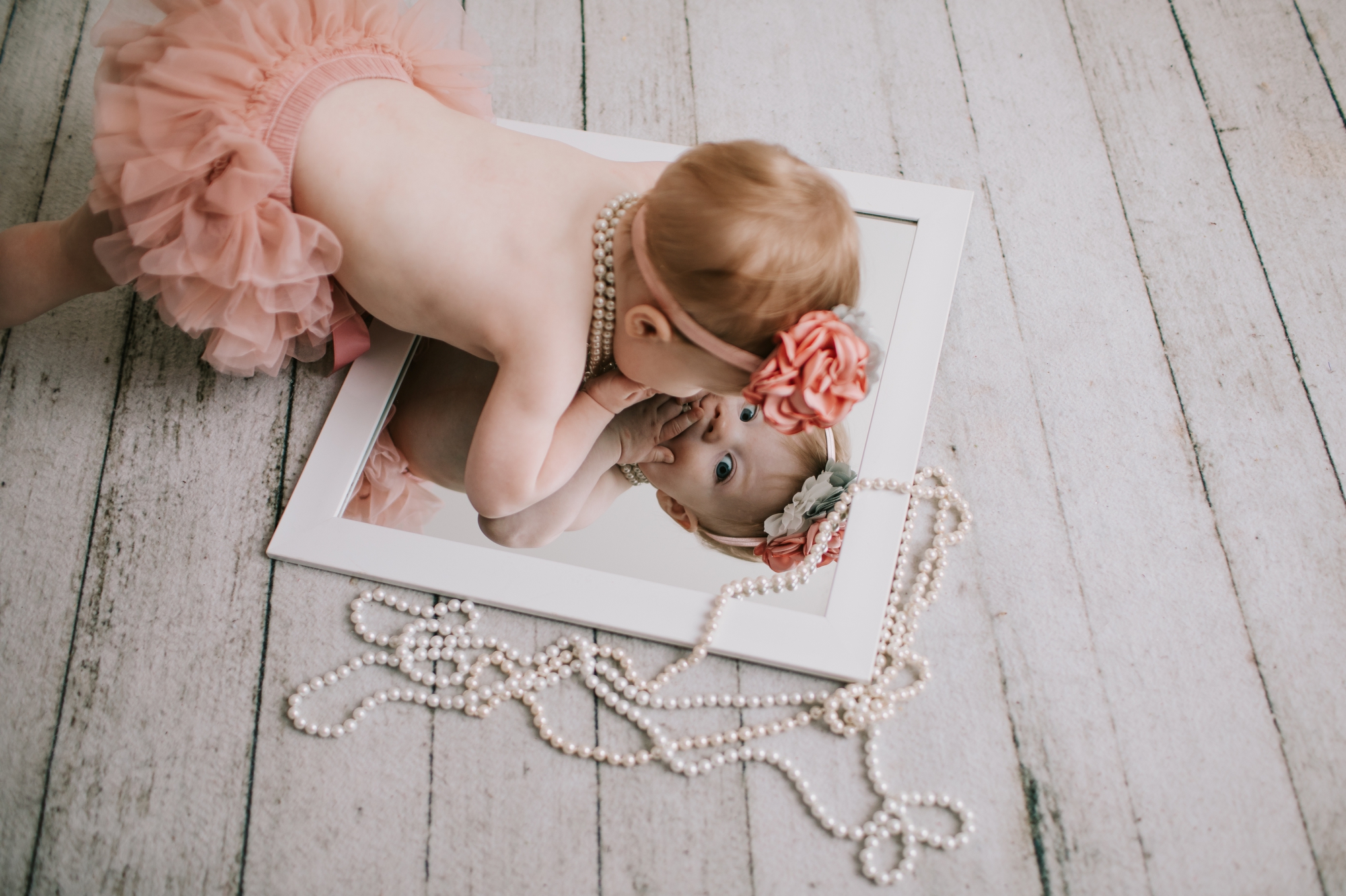 Silly image of baby looking at herself in the mirror.  Baby Photographer 63090